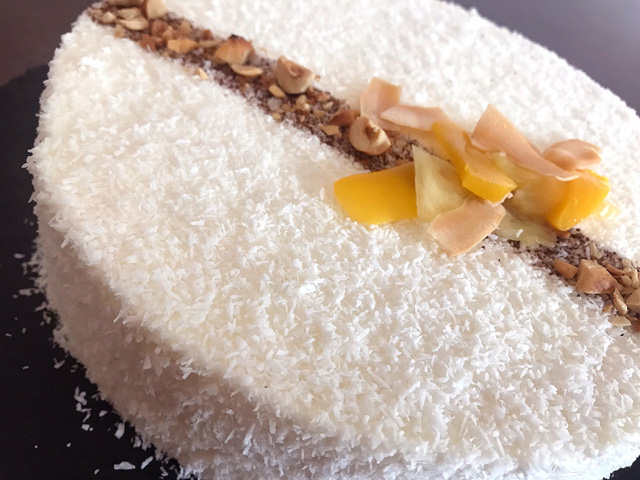 Entremets tropical mangue coco framboise : biscuit dacquoise, mousse coco, insert fruité et finition élégante à la noix de coco râpée