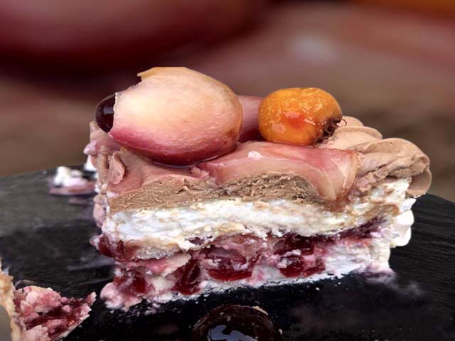 Pavlova pêche Amarena : meringue suisse croustillante, compotée de pêches et cerises, ganache chocolat au lait et chantilly à la pêche