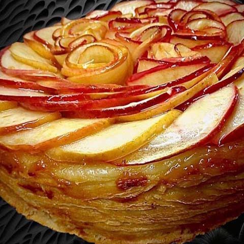 Une magnifique tarte aux pommes, à la pâte feuilletée striée, garnie d'une délicieuse crème aux pralines roses de Lyon, d'une brunoise de pommes caramélisées au rhum, et d'une compotée, le tout coiffé de pommes coupées à la mandoline
