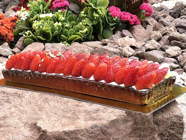 Tarte aux fraises maison garnie d’une ganache vanille onctueuse, avec des fraises fraîches disposées sur une pâte sucrée croustillante.