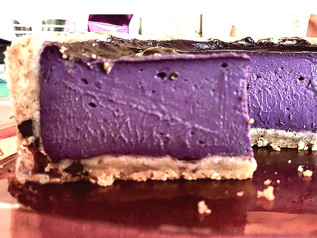 Part de Flankie à l’ube révélant un flan pâtissier crémeux violet sur une épaisse pâte cookie aux pépites de chocolat