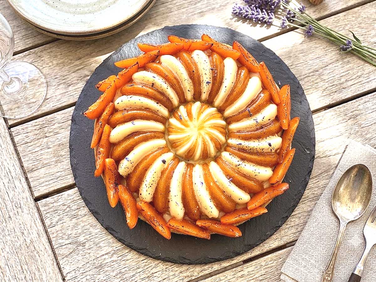 Vue de dessus d'une tarte aux abricots décorée de segments d'abricots frais et d'un crémeux chocolat blanc.